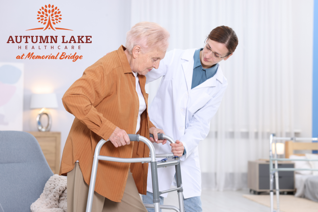 A healthcare worker assists an elderly woman using a walker in a nursing home setting.